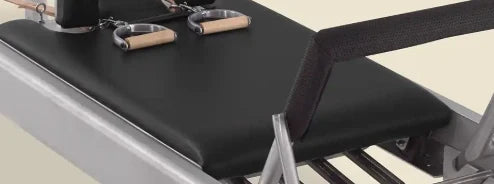 Black pre-stitched upholstery fitted on a Gratz Pilates reformer carriage with wooden handles.