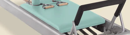 Fjord blue pre-stitched upholstery fitted on a Gratz Pilates reformer carriage with wooden handles.