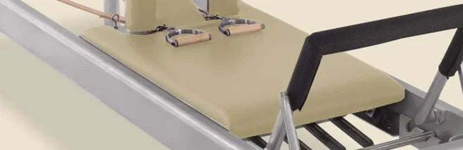 Bone-colored pre-stitched upholstery fitted on a Gratz Pilates Reformer carriage with shoulder rests.