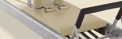 Bone-colored pre-stitched upholstery fitted on a Gratz Pilates Reformer carriage with shoulder rests.