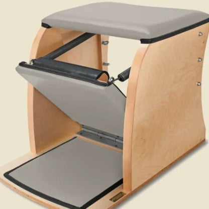 Dove grey pre-stitched upholstery fitted on a wooden Pilates Wunda Chair with pedal pads.