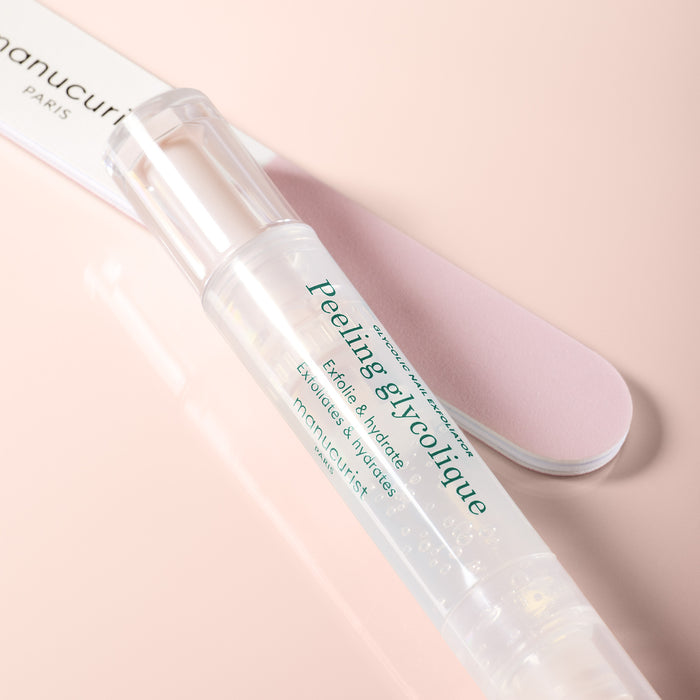 A clear, pen-shaped Prep  Glow Routine by Manucurist rests on a pink surface beside a light pink nail file—ideal for exfoliating and hydrating nails and cuticles to achieve glossy nails in your care routine.