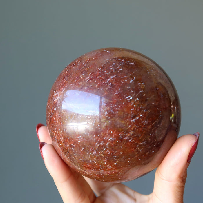 hand holding red hematite quartz sphere