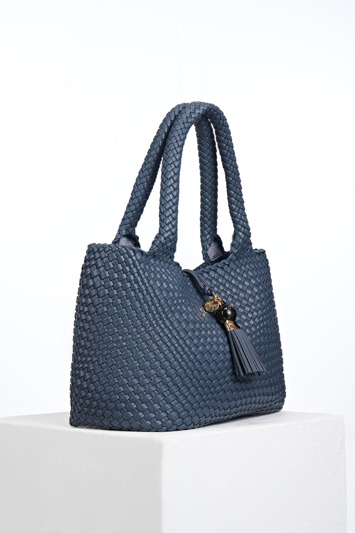 Side view of Saskia Denim Blue faux leather Woven Tote with Thames Tassel closure detail