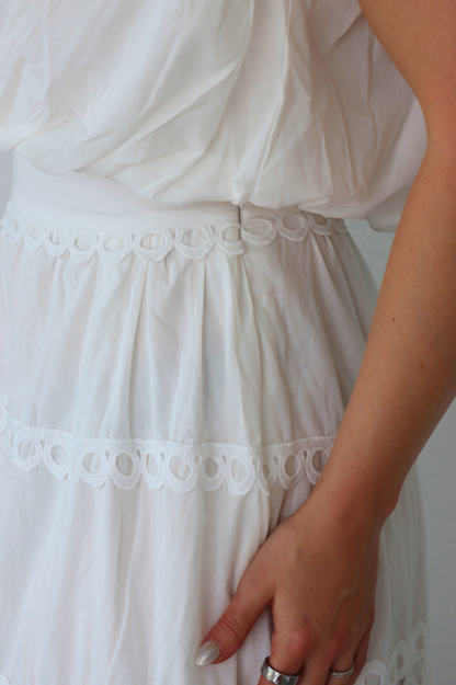 girl wearing matching white set; long skirt and tank top