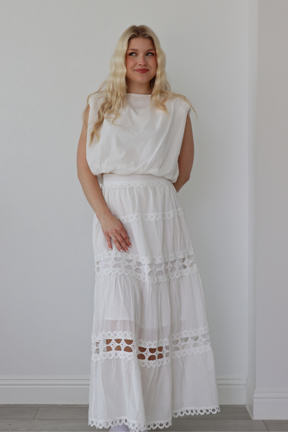 girl wearing matching white set; long skirt and tank top