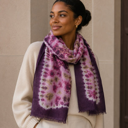 Woman wearing a purple tie-dye scarf against a beige wall