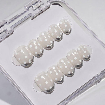 EyeCandys Silver Spotted Press-On Nails feature a light beige base with white polka dots, neatly arranged in two rows inside a clear case for an easy salon-gel manicure at home.