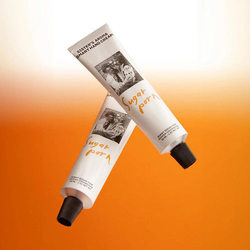 Two tubes of sister's aroma sugar porn  hand cream on an orange background