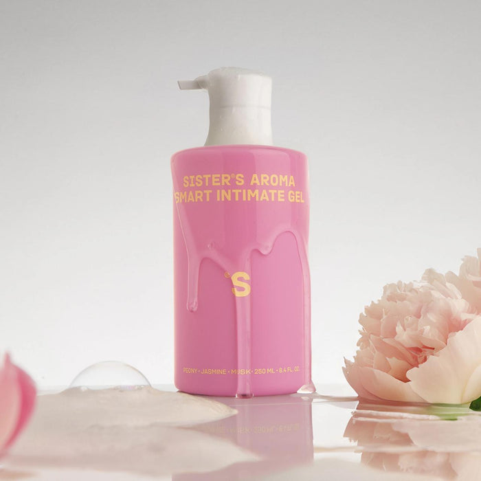 Pink bottle of Sister's Aroma intimate gel Peony with peony flower  on a reflective surface