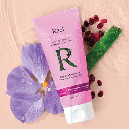 Rael Soothing Gel to Foam Feminine Wash on a water background styled with a purple flower, aloe vera and pomegranate seeds.
