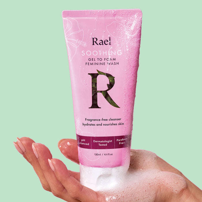 A hand holding a pink tube of Rael Soothing Vulva Care Gel-to-Foam Feminine Wash.