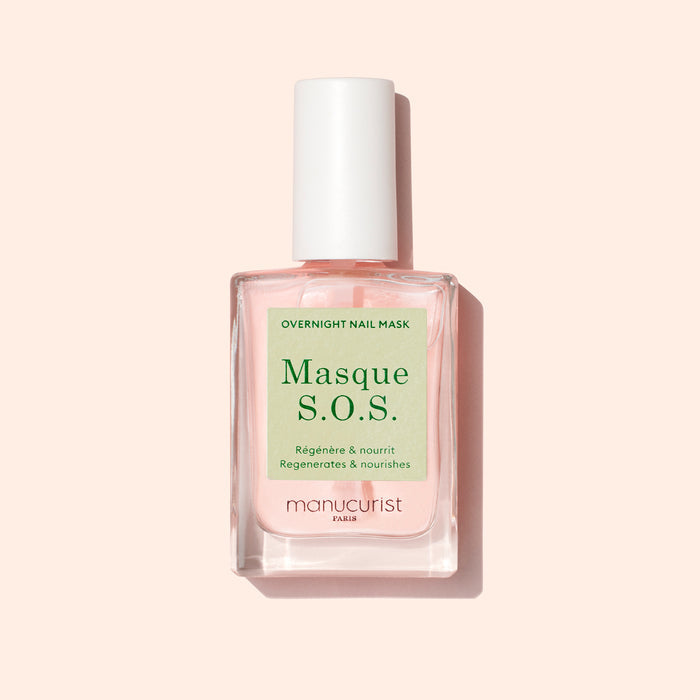 A bottle of Manucurist S.O.S. Nail Mask, a hydrating nail treatment with pink liquid and a white cap, sits against a light pink background. The label shows both French and English text.