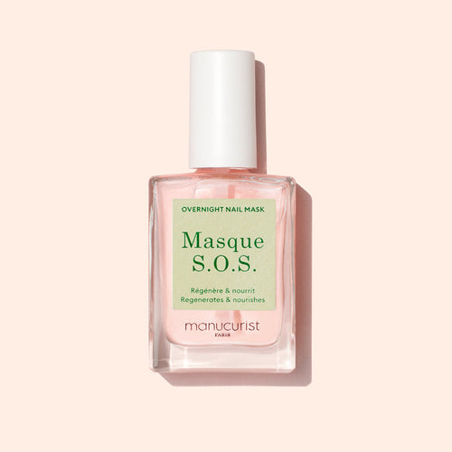 A bottle of Manucurist S.O.S. Nail Mask, a hydrating nail treatment with pink liquid and a white cap, sits against a light pink background. The label shows both French and English text.