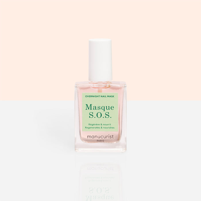 A clear glass bottle of Manucurist S.O.S. Nail Mask, a hydrating nail treatment with a white cap and light pink liquid, sits against a pastel peach and white background.