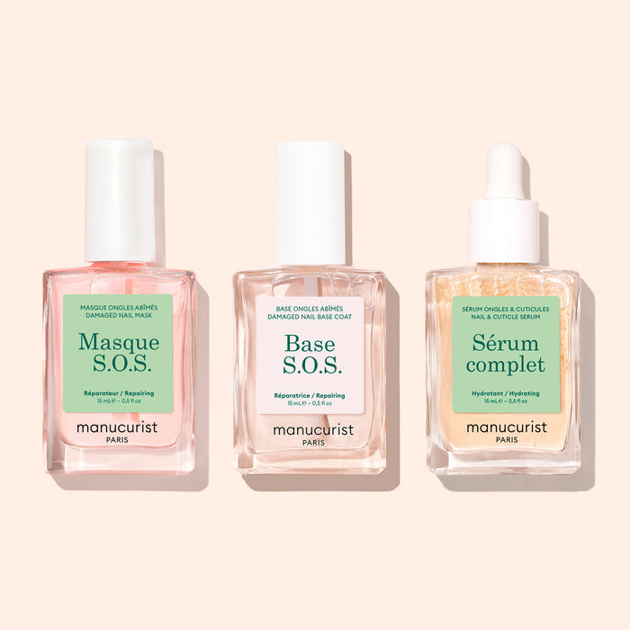 Three clear glass bottles with white tops, labeled S.O.S. Nail Mask by Manucurist, are arranged side by side on a light beige background.