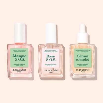 Three clear glass bottles with white tops, labeled S.O.S. Nail Mask by Manucurist, are arranged side by side on a light beige background.