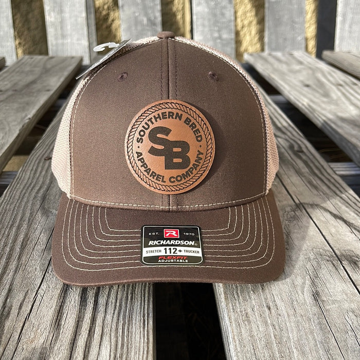 A brown and beige Southern Bred Apparel Company cap with a leather logo patch on the front.