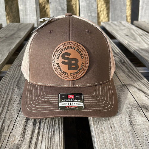 A brown and beige Southern Bred Apparel Company cap with a leather logo patch on the front.