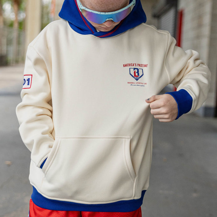 Close up of boy wearing a cream stadium hoodie with royal blue hood and cuffs