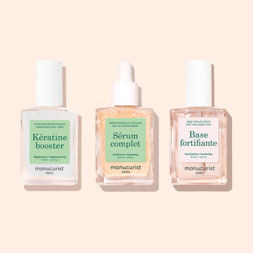 Three square glass bottles from Manucurist’s "Basic Routine - Soft Nails" set are arranged side by side on a light beige background. Designed for your nail care routine, each bottle features a white cap and a distinct label—Kératine booster, Sérum complet, and Base fortifiante—making this Manucurist collection ideal for anyone with soft nails seeking an effective strengthening solution.