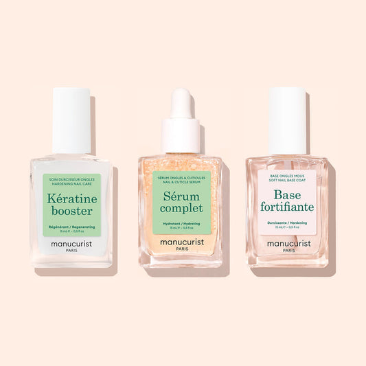 Three square glass bottles from Manucurist’s "Basic Routine - Soft Nails" set are arranged side by side on a light beige background. Designed for your nail care routine, each bottle features a white cap and a distinct label—Kératine booster, Sérum complet, and Base fortifiante—making this Manucurist collection ideal for anyone with soft nails seeking an effective strengthening solution.
