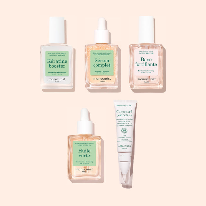 Manucurist’s Starter Routine - Soft Nails features five green and white-labeled nail care essentials—booster, serum, base, oil, and a tube of perfecting concentrate—artfully arranged on a pale peach background for the ultimate routine to strengthen soft nails.