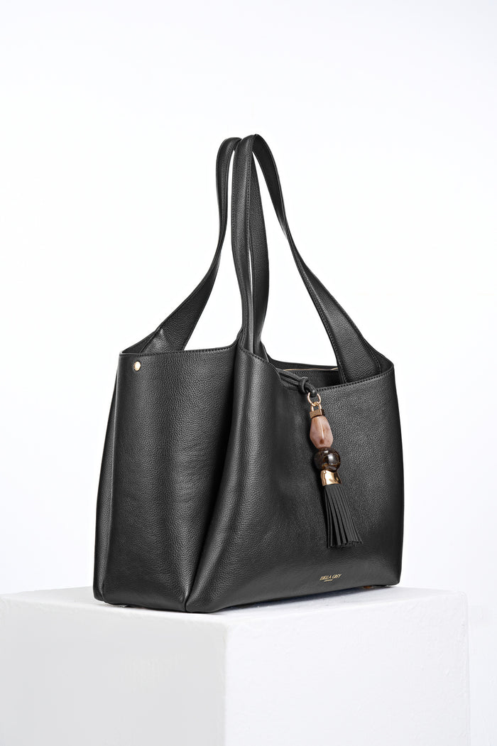 Side view of Stella Black faux leather Laptop Tote with Mayfair Tassel Closure detail