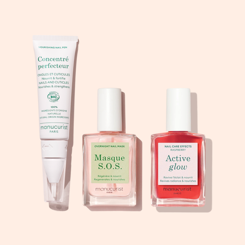 Manucurist’s Strong Glow Trio for nail care is shown on a light pink background: a Concentré Perfecteur tube, a Masque S.O.S. bottle for damaged nails, and an Active Glow red polish bottle.