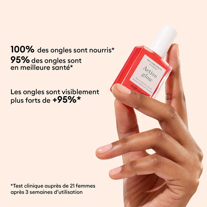 A manicured hand holds a pink bottle of Manucurist Strong Glow Trio. French text claims nourished, healthier, and stronger nails after three weeks of use in a clinical test with 21 women.