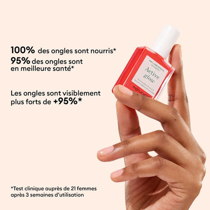A manicured hand holds a pink bottle of Manucurist Strong Glow Trio. French text claims nourished, healthier, and stronger nails after three weeks of use in a clinical test with 21 women.