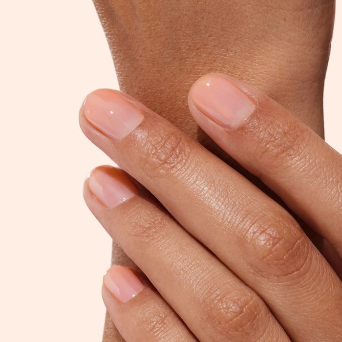 A close-up of neatly manicured nails showcases a natural, glossy nude look achieved with Manucurist’s Strong Glow Trio—a set designed to restore and strengthen damaged nails for a healthy, well-shaped appearance.