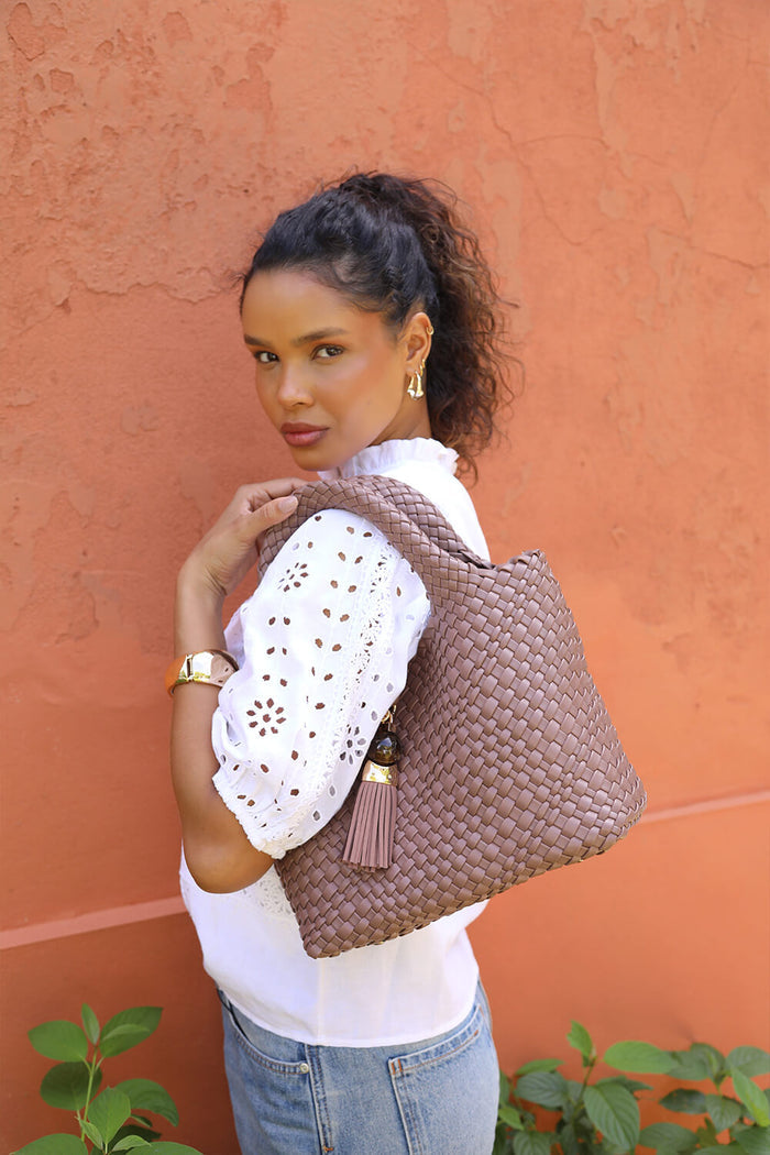 Female model wearing Suky Fawn faux leather Woven Crossbody over her shoulder using the top grab handles