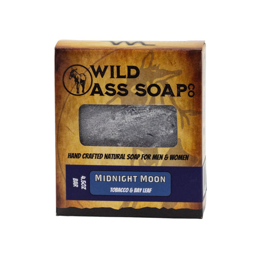 A packaged bar of soap labeled 'Wild Ass Soap Co. Midnight Moon' with a window showing the gray bar of soap inside.