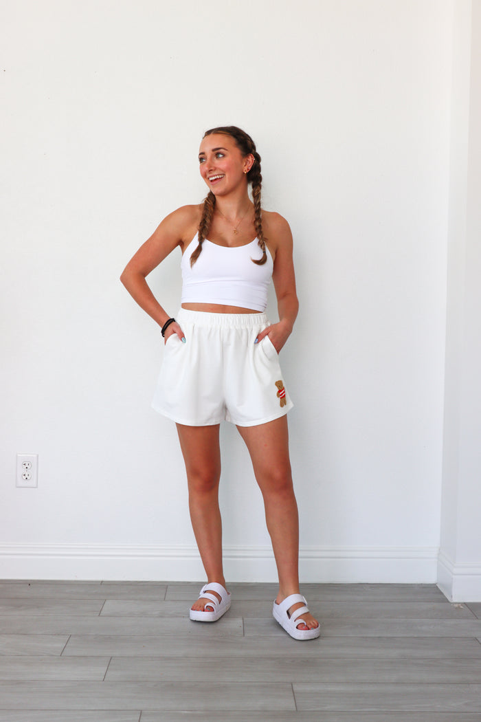 girl wearing white lounge shorts with a teddy bear patch