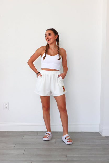 girl wearing white lounge shorts with a teddy bear patch