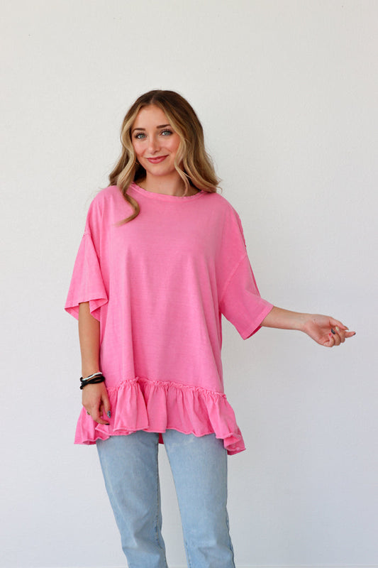 Woman wearing a pink ruffled top and light blue jeans against a white background