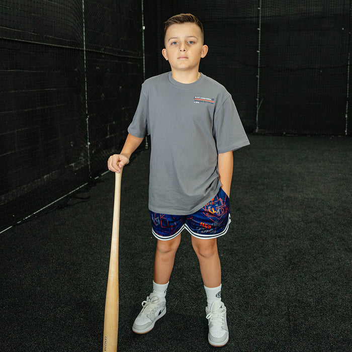Child holding a baseball bat in an indoor batting cage