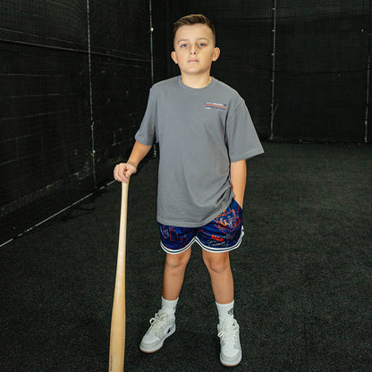 Child holding a baseball bat in an indoor batting cage