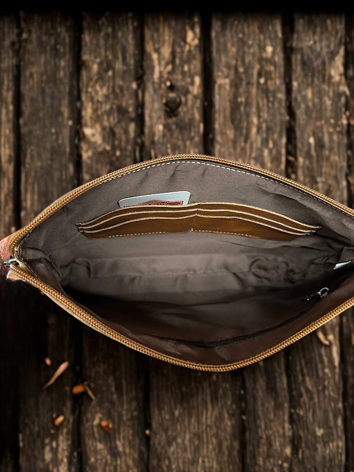 This Brown tooled leather and cowhide purse features a removable adjustable shoulder strap and a zippered closed concealed carry pocket on the rear. Inside it has six card slots and a zippered closed pocket. Inside View