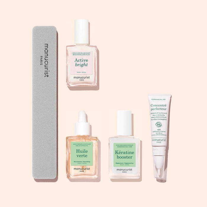 The Manucurist Starter Routine - Yellow Nails set includes five essential nail care products—a nail file and four treatment bottles (Active Bright, Huile Verte, Kératine Booster, and Concentré Perfecteur)—all arranged neatly on a pale pink background, perfect for brightening polish and strengthening nails.