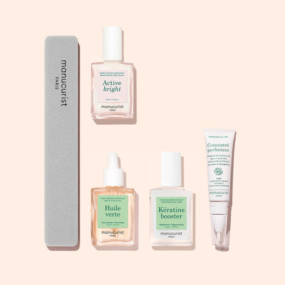 The Manucurist Starter Routine - Yellow Nails set includes five essential nail care products—a nail file and four treatment bottles (Active Bright, Huile Verte, Kératine Booster, and Concentré Perfecteur)—all arranged neatly on a pale pink background, perfect for brightening polish and strengthening nails.