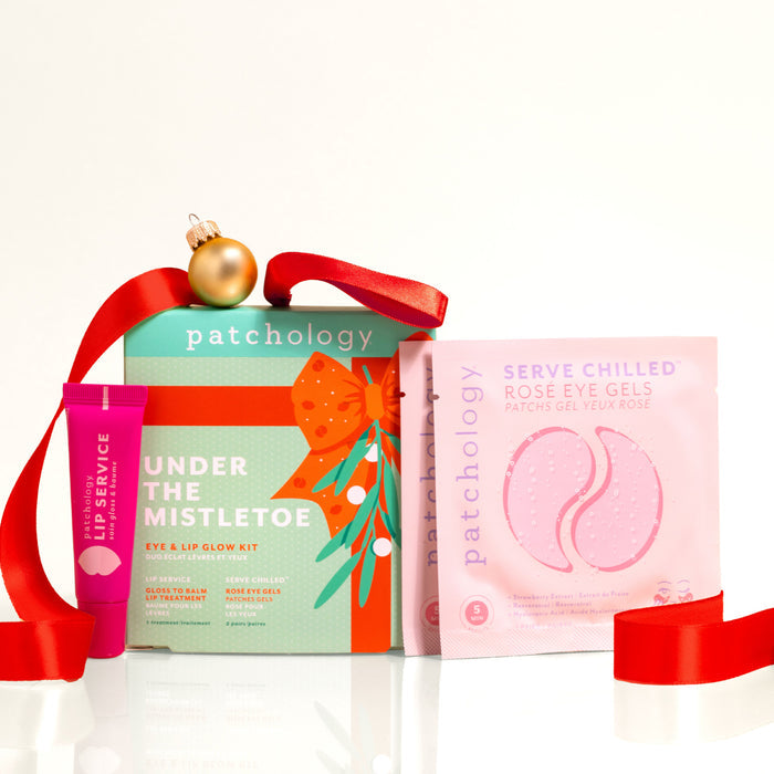 Under the Mistletoe eye and lip glow kit with a red ribbon hanger, shown with two rosé eye gel pouches and a pink gloss-to-balm lip treatment