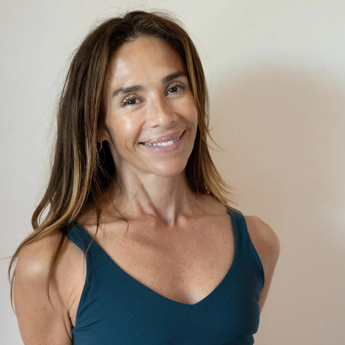 Smiling woman with long brown hair wearing a teal sleeveless top against a neutral background for a mindful wellness event by BuDhaGirl