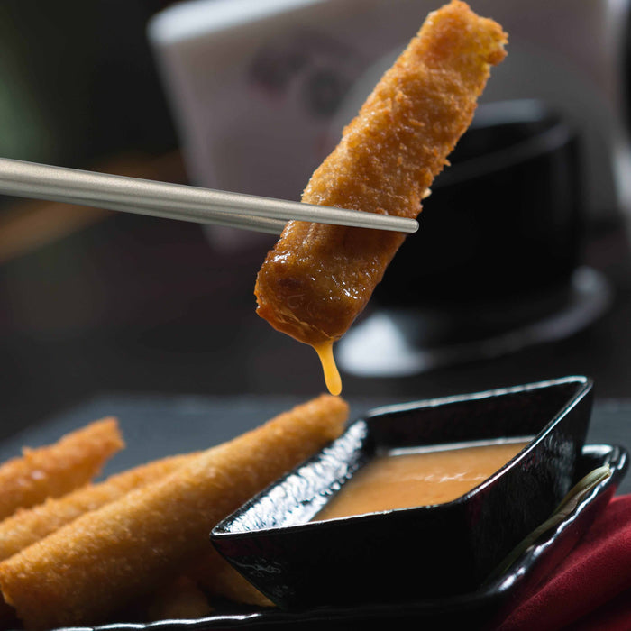 Winnerwell® square titanium chopsticks picking up a piece of food, illustrating their functionality in eating scenarios.