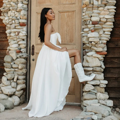A life style photo of a women wearing a pair of white smooth leather women's Dingo boot with a snip toe and a western heel.