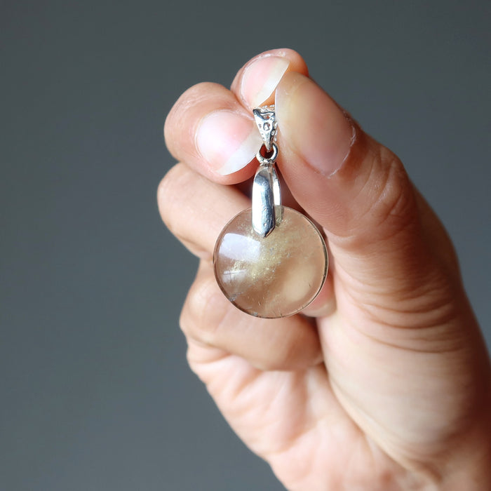 hand holding yellow quartz pendant
