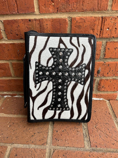 A Bible cover with a zebra print cowhide background and a studded cross in the center, predominantly black and white.