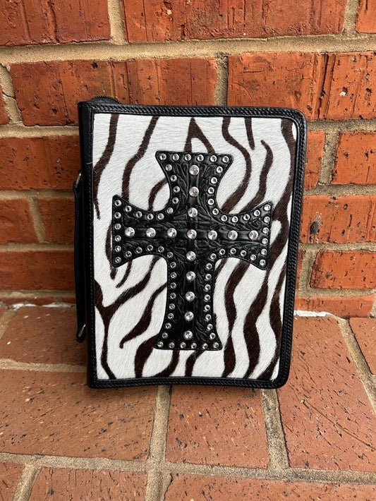 A Bible cover with a zebra print cowhide background and a studded cross in the center, predominantly black and white.